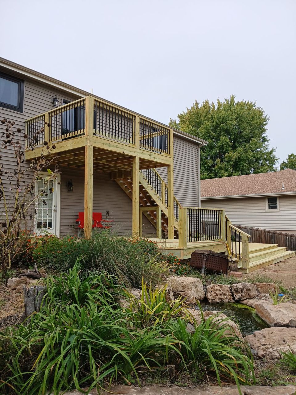 Completed elevated wood deck with dark railings and stairs to the yard