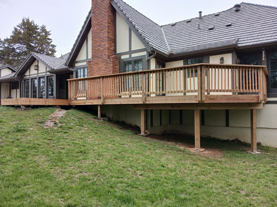 Completed wood deck with railings along the back of a home